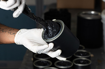 Worker handling black coating material in a container